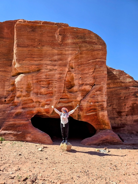 A person joyfully standing in front of a rock formation