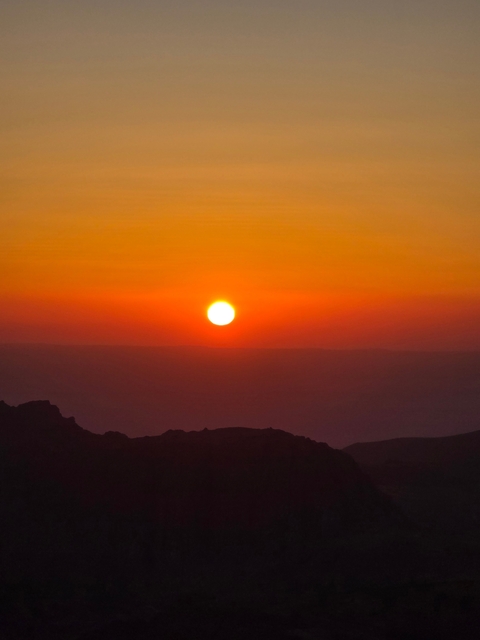       A bright orange sunset view over rocky terrain
  