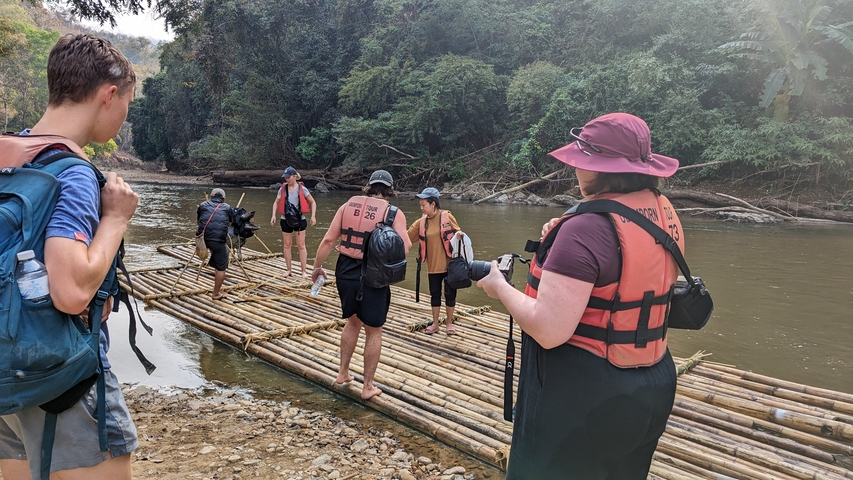 People preparing to raft down a river on bamboo rafts.