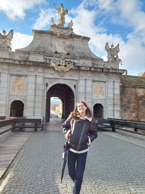       Person standing in front of a decorative archway entrance.
  