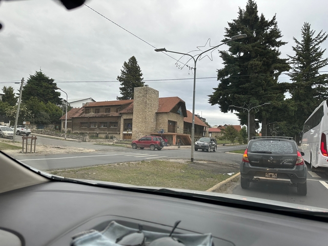       Street view with cars and stone buildings under a cloudy sky.
  