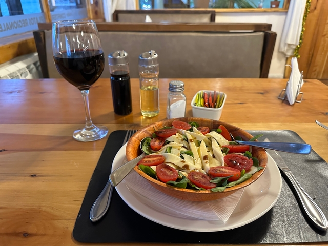       A salad with cherry tomatoes and mozzarella served with a glass of red wine.
  
