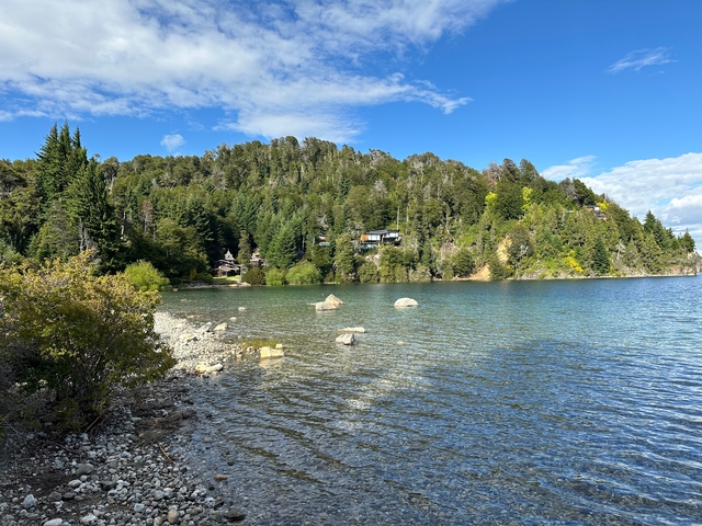       Clear lake surrounded by trees and rocky shore.
  