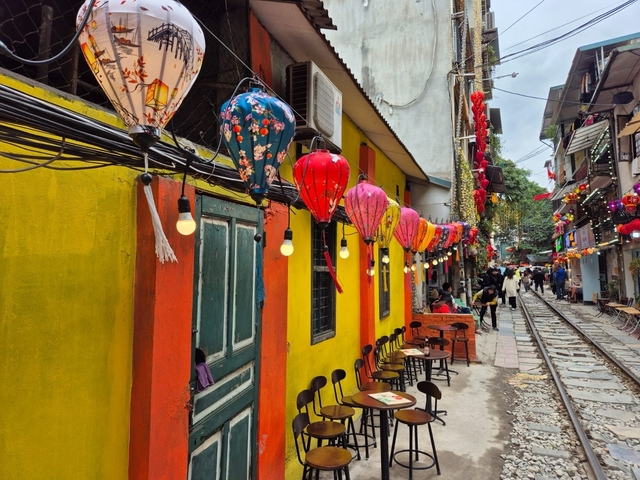       Vibrant street with colorful lanterns and railway.
  
