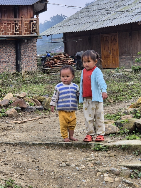       Two children standing outdoors on a rocky path.
  