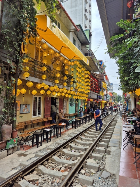       Decorative street with yellow lanterns above railway track.
  
