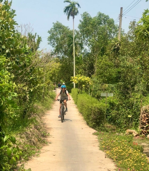       People cycling on a forest trail amidst lush greenery.
  