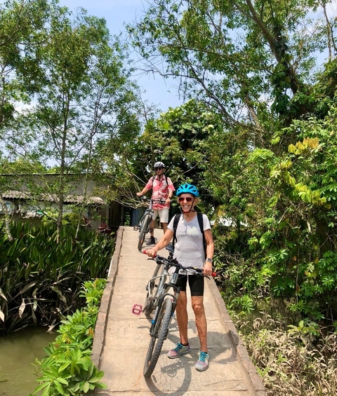 Cyclists posing on a narrow path surrounded by dense foliage.