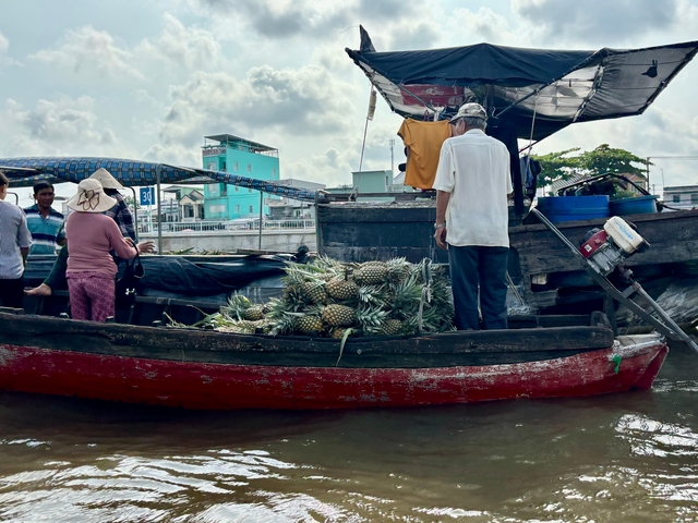 Floating market scene with people and goods on a boat.