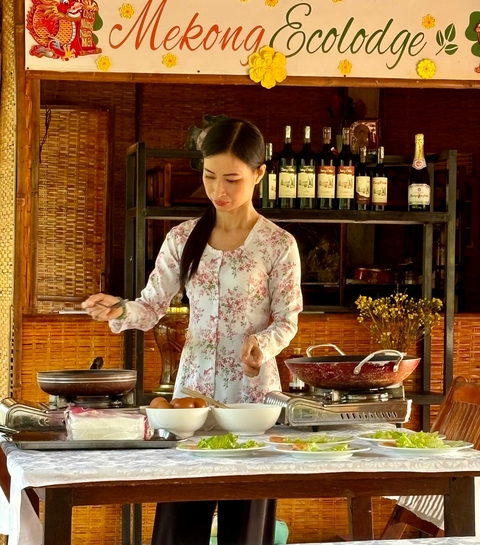       Woman preparing food in an open kitchen with traditional utensils.
  