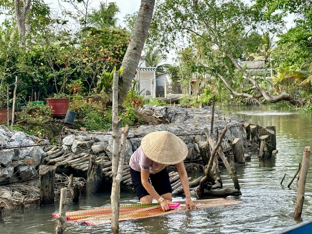 Person washing clothes by a canal.