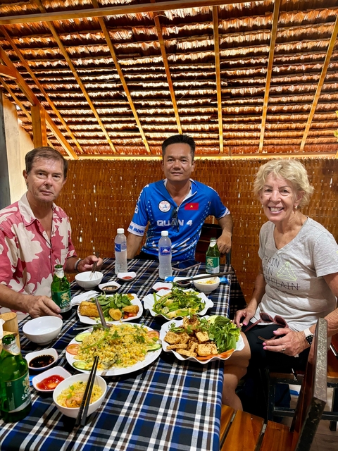 Three people dining with traditional Vietnamese food.