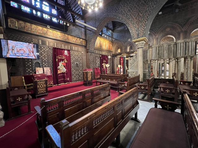       Interior of a church with wooden pews and ornate decorations.
  