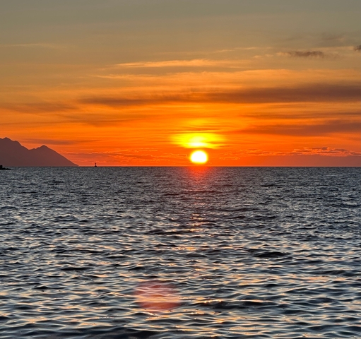A stunning sunset over the ocean with distant mountains.