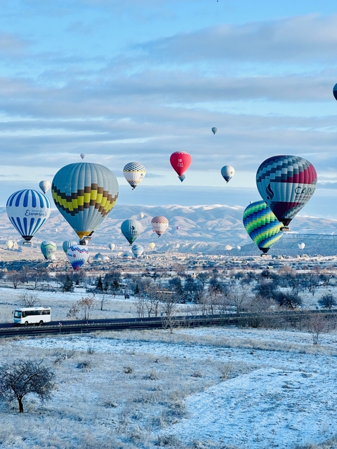       Colorful hot air balloons floating above a snowy landscape.
  