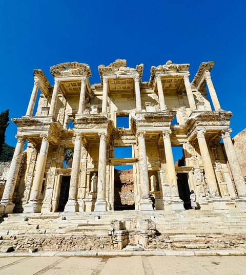       Facade of an ancient library with detailed carvings and bright sky.
  
