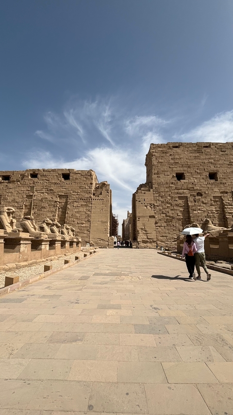 People walking through an ancient temple with tall statues.