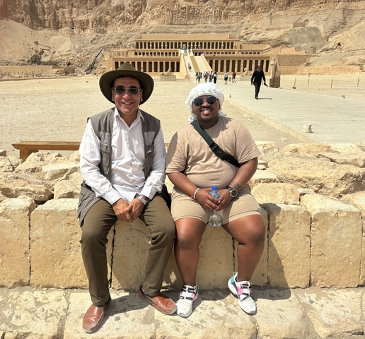 Two people sitting on ancient stone ruins.