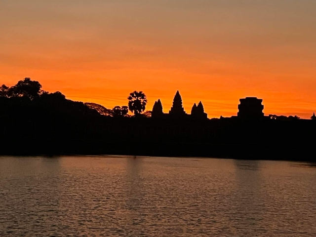 Silhouette of Angkor Wat against an orange sunset.