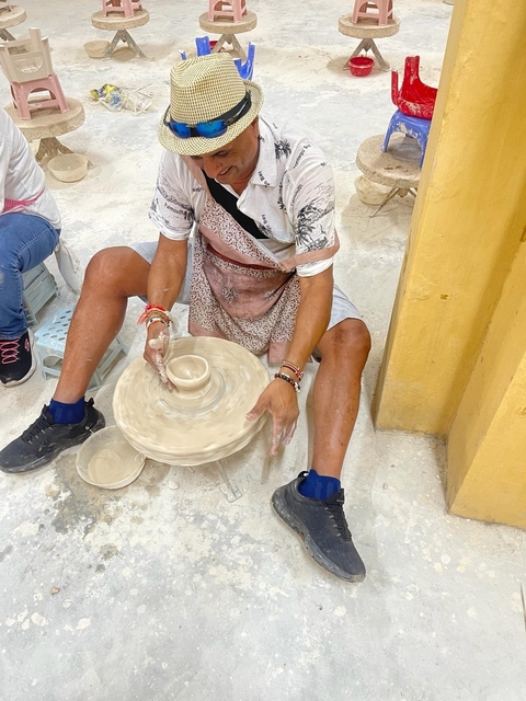 Person making pottery by hand on a wheel.