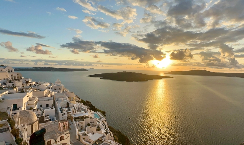 Sunset over the sea with Santorini buildings.