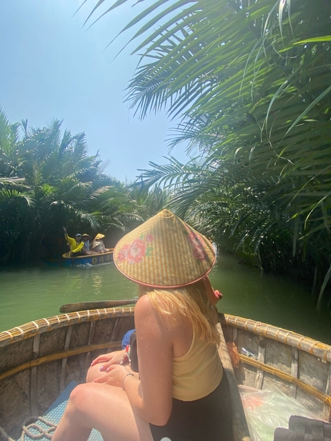       People in traditional boats in a waterway surrounded by tropical vegetation.
  