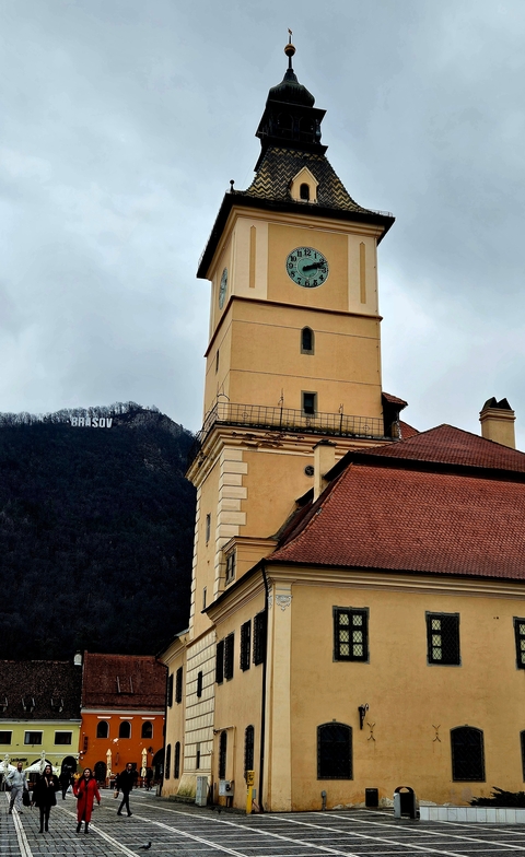       Historical building tower with Brasov lettering on hillside.
  
