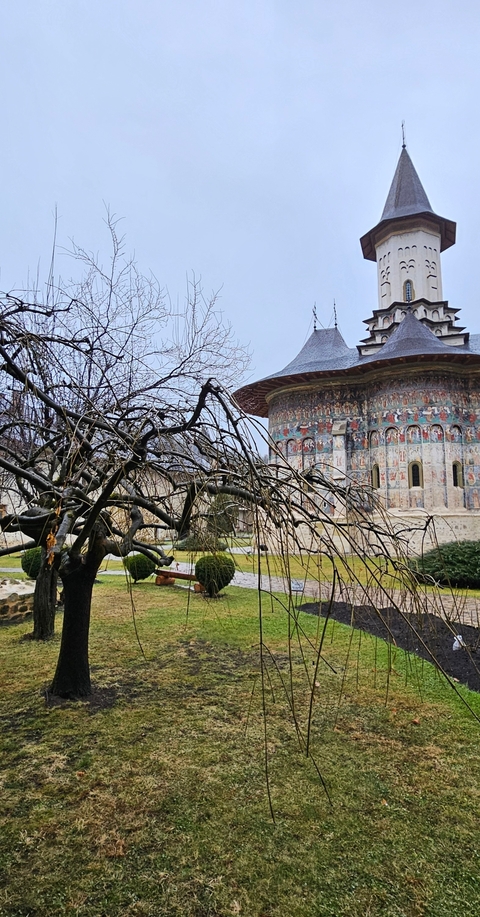 Monastery with wall paintings and barren trees.
