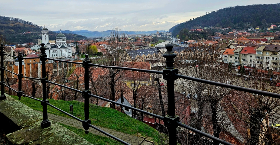 Elevated view of a cityscape with a church and rolling hills in the background.