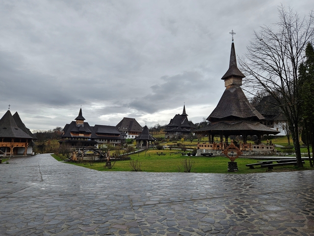       Traditional wooden buildings and churches in a rural setting with overcast skies.
  