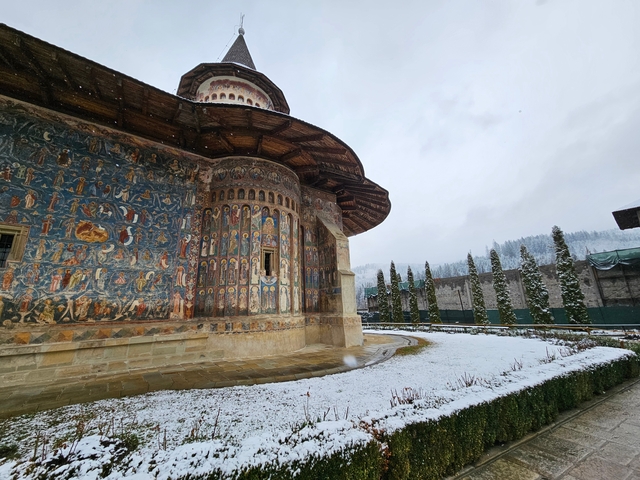 Colorful frescoes on the walls of a historic church in a snowy landscape.