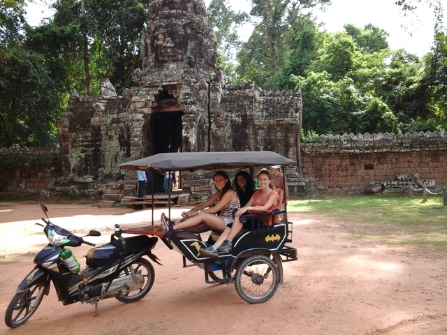 Group on a tuk-tuk in front of ancient ruins.