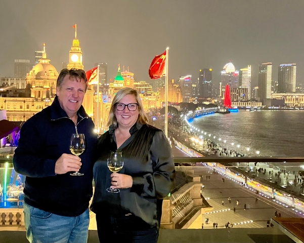 Couple enjoying a scenic night view of Shanghai skyline with wine glasses.