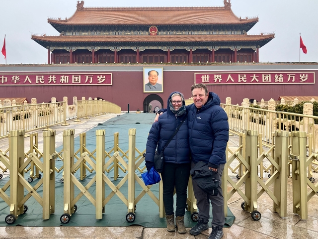 Couple posing in front of Tiananmen Square's entrance with Mao Zedong's portrait.