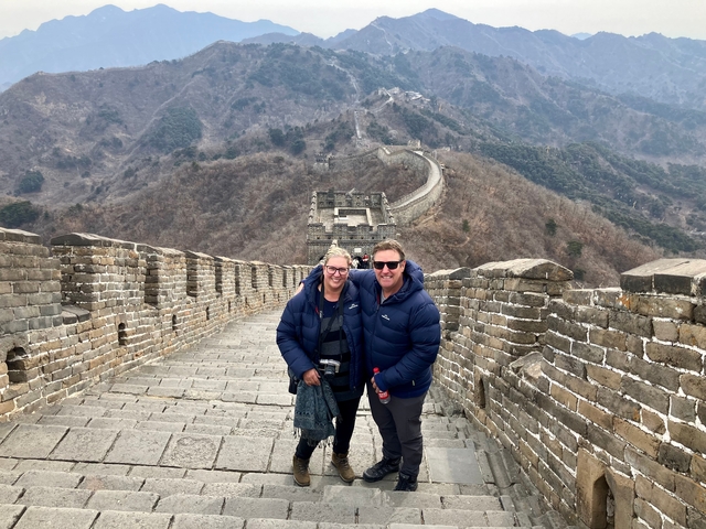 Couple standing on the Great Wall of China with scenic views behind them.
