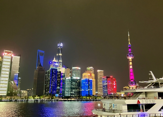       Night view of Shanghai's skyline featuring brightly lit modern skyscrapers.
  