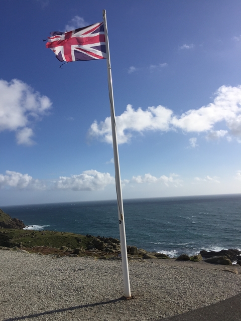 Sky and ocean with a flagpole in the foreground.