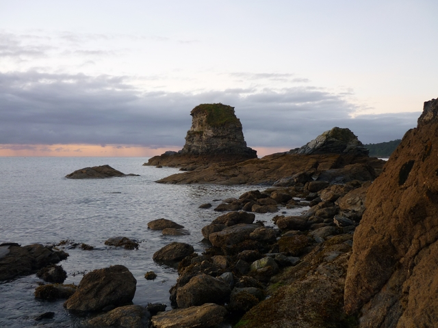 Rocky coastline with sea stacks at sunset.