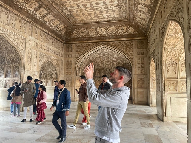 Interior of a historic monument with ornate carvings and people taking photos.