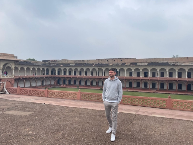 A person standing in a courtyard of a large historical structure.