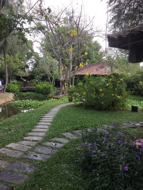       Lush garden with a small bridge over a stream.
  