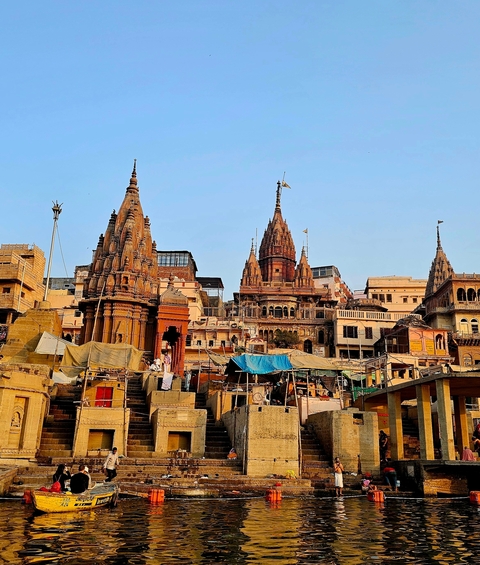       Panoramic view of Varanasi ghats with temples and boats.
  