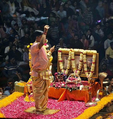       Person performing a ritual with flowers and incense at night.
  