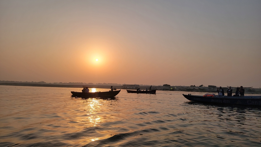       Silhouetted boats on a river at sunrise.
  