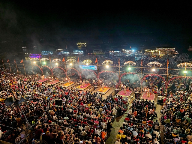       Night view of a crowded riverbank with illuminated platforms.
  