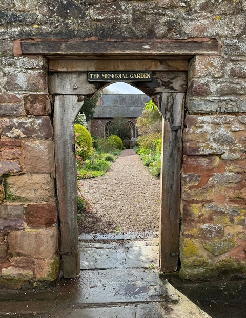 A garden path leads through stone entrance to an ornate church
