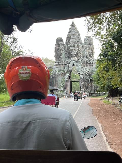 Passenger view from a tuk-tuk approaching stone structure