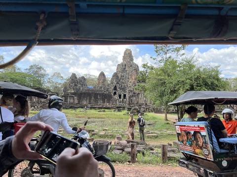       People on a tuk-tuk observing stone ruins
  