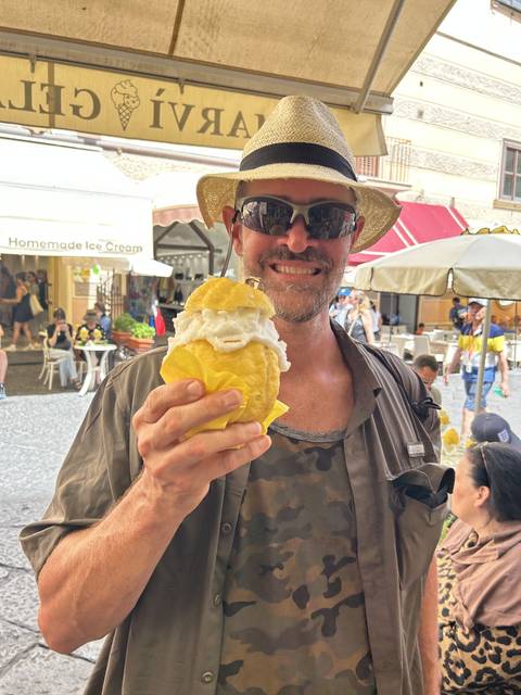       Person holding a large gelato cone with a big smile.
  
