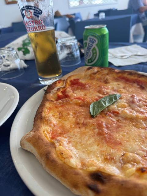 Plate of pizza with a drink and beer on a table.